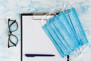 Medical protective masks and glasses with pen on doctor's tablet