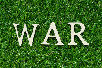 Wood alphabet letter in word war on green grass background