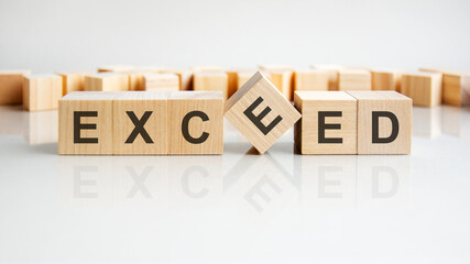 exceed text on a wooden blocks, gray background