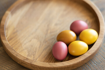 On a round wooden tray are five brightly colored Easter eggs and space for text.