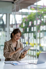 Fototapeta premium Smiling Asian girl student write on the tablet to study language online watch and listen to the lecturer, webinar via video call e-learning at home, distance education