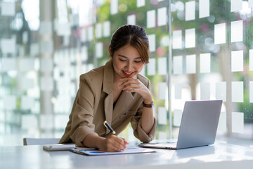 Fototapeta premium Charming asian businesswoman sitting working on laptop in office.