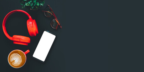 Office desk with  Blank screen smart phone, headphone, cup of coffee, eyeglass on dark background, Top view , Mock up.