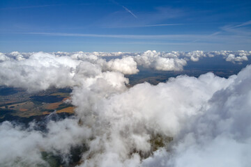 Obraz premium Aerial view from airplane window at high altitude of earth covered with puffy cumulus clouds forming before rainstorm