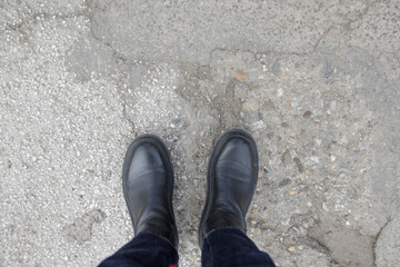 Person in chunky platform leather boots on asphalt, top view