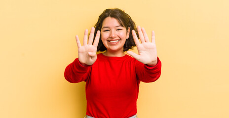 pretty hispanic woman smiling and looking friendly, showing number nine or ninth with hand forward,...