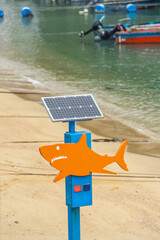 Solar-powered megaphones pole with warning sign caution sharks.