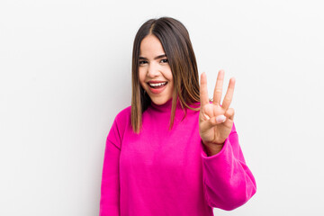 pretty hispanic woman smiling and looking friendly, showing number three or third with hand...