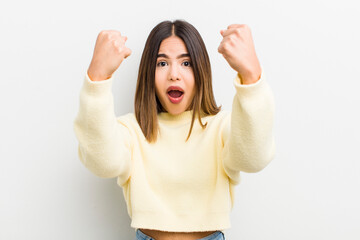 pretty hispanic woman celebrating an unbelievable success like a winner, looking excited and happy...