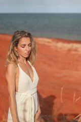 Fototapeta na wymiar Close up portrait of beautiful young woman on red sand beach