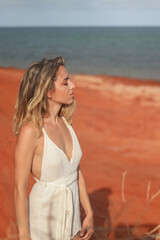 Fototapeta na wymiar Profile portrait of beautiful young woman on red sand beach