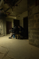 View of a bomb-shelter with caucasian guy and black guy are sitting and having a talk near laptop...