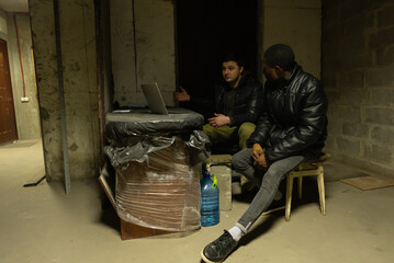 Caucasian guy and black guy are hiding in a bomb-shelter during a war and emotionally discuss the...
