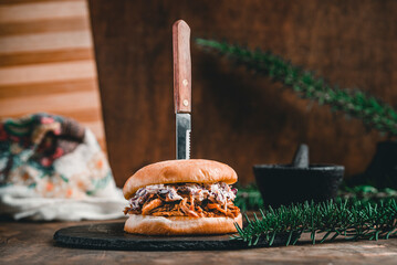 Front shot of a delicious meat sandwich with artisan bread pierced by a knife.
