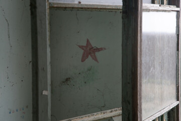 Red star as a symbol of communism on the wall in the demolished abandoned building