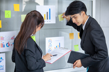 Business people meeting at office and use post it notes to share idea. businessman and businesswoman putting colorful sticky notes on glass window in office.