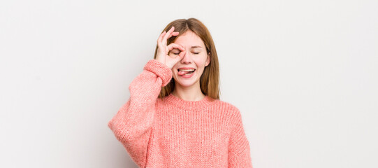 red head pretty woman smiling happily with funny face, joking and looking through peephole, spying...