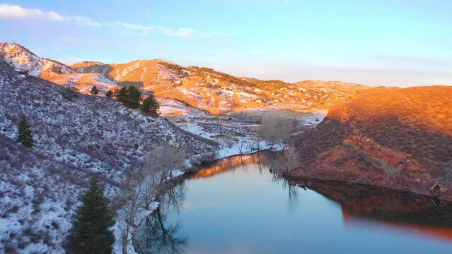 Aerial drone shot over lake Molas with snow covered hills on both sides at sunset. Sun rays falling on the mountain peaks in Colorado, United States.