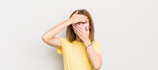 red head pretty woman covering face with both hands saying no to the camera! refusing pictures or...