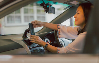 Woman driver hand adjust cell phone in stand holder for direction.
