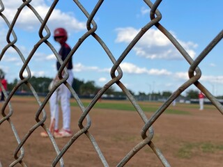 Kids playing baseball at a baseball field batter 
catcher 
fence 