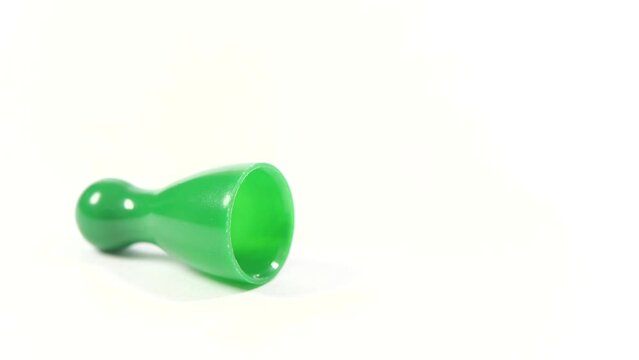 Finger tipping over, knocking over a single green game piece, defeat, unfair fight destabilizing a structure, aggressor, aggressive behavior symbol, loss of balance abstract concept, white background