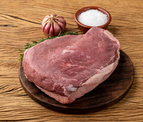 Raw picanha or rump meat over wooden board with seasonings