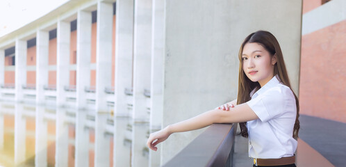 Portrait of an adult Thai student in university student uniform. Asian beautiful girl sitting smiling happily at university