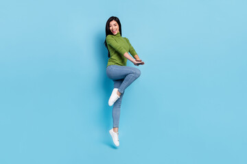 Full size photo of impressed young brunette lady jump yell wear jumper jeans shoes isolated on blue background