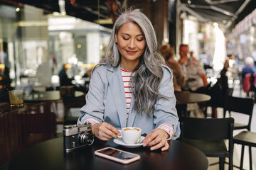 Asian woman having cup of coffee in cafe