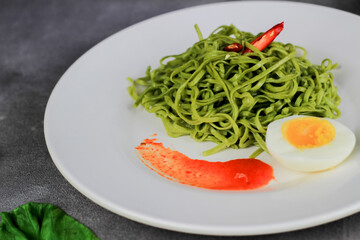 Mie Goreng. Fried noodles served with fried eggs and vegetables on a plate.