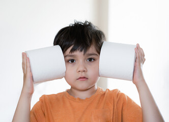 Portrait young boy with looking out and playing with toilet paper, Kid putting  toilet roll on his...