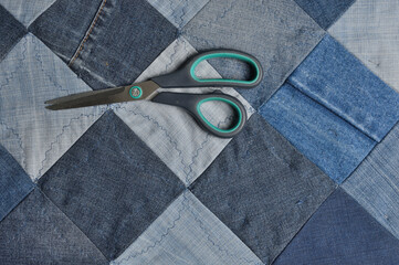 scissors lying on top of a canvas sewn from pieces of denim.