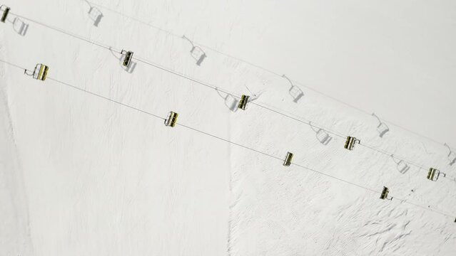 Aerial view of Livigno ski resort in Lombardy, Italy. Chairlifts, ski lifts, gondola cabin lifts are moving. View from above, top view. 4k video 