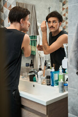 Male model applying brow gel for eyebrows while preparing to the walking
