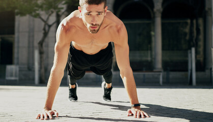 Fototapeta premium Be the strongest you can be. Shot of a young man doing pushups during his workout in the city.