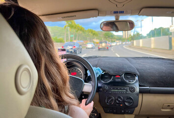 Woman driving in Hawaii, USA. View from inside the vehicle. Young woman is driving a car. A day...