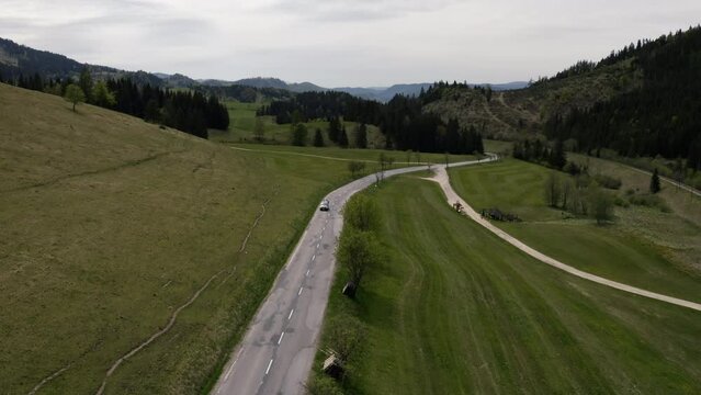 VW van driving in alone road, sunny, drone shot. Van life trip. Areal view on nature. 