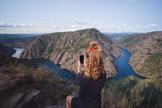 Anonymous female tourist taking photo of picturesque mountains