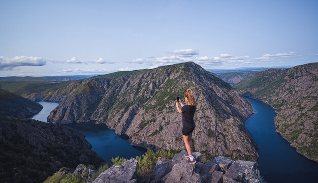 Anonymous female tourist taking photo of picturesque mountains
