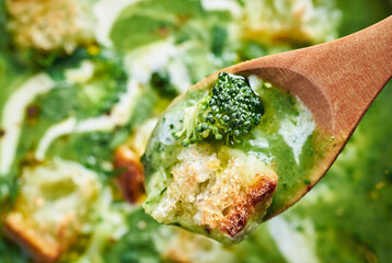 Fresh creamy broccoli soup closeup. Closeup of green healthy vegan broccoli soup in spoon.