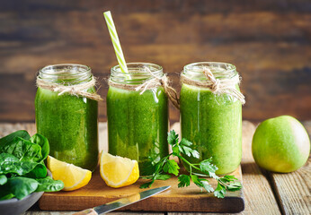 Fresh green vegan detox smoothie.Fresh healthy green spinach and apple smoothie served in jar with lemon for diet and detox.