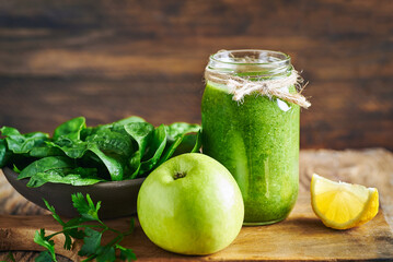 Fresh green vegan detox smoothie.Fresh healthy green spinach and apple smoothie served in jar with lemon for diet and detox.