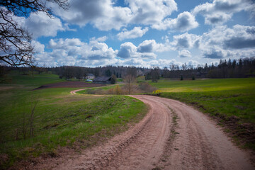 Fototapeta na wymiar A beautiful springtime landscape with a gravel road. Dirt road in Northern Europe.