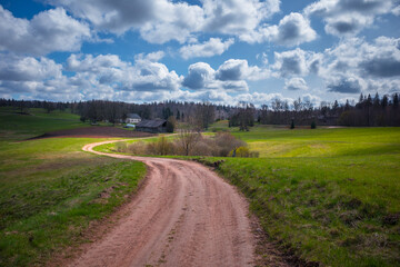 Fototapeta na wymiar A beautiful springtime landscape with a gravel road. Dirt road in Northern Europe.