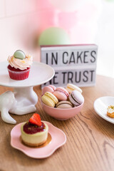 Cupcakes and macaroons in a candy store . Delicious treats for birthdays or weddings. Pastry shop in pink flowers