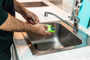 Unrecognizable person washing dishes by hand.
People, man doing housework, equality
