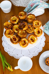 Traditional portuguese cakes called Pasteis de Belem on laid table with white lace napkins 
