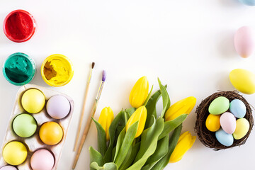 Stylish background with colorful easter eggs isolated on white background with yellow tulip flowers. Flat lay, top view, mockup, overhead, template