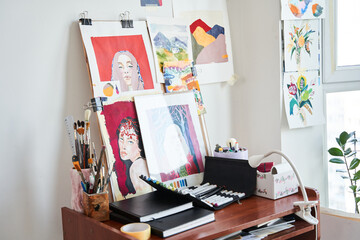 Beautiful empty artist's studio with bright natural light and a lot of pictures and artistic tools at the table